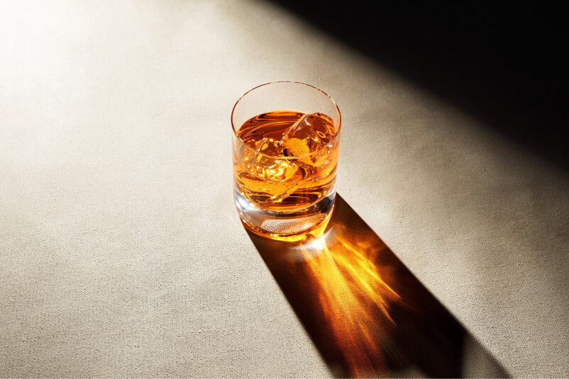 Glas mit Whisky und harten Schatten