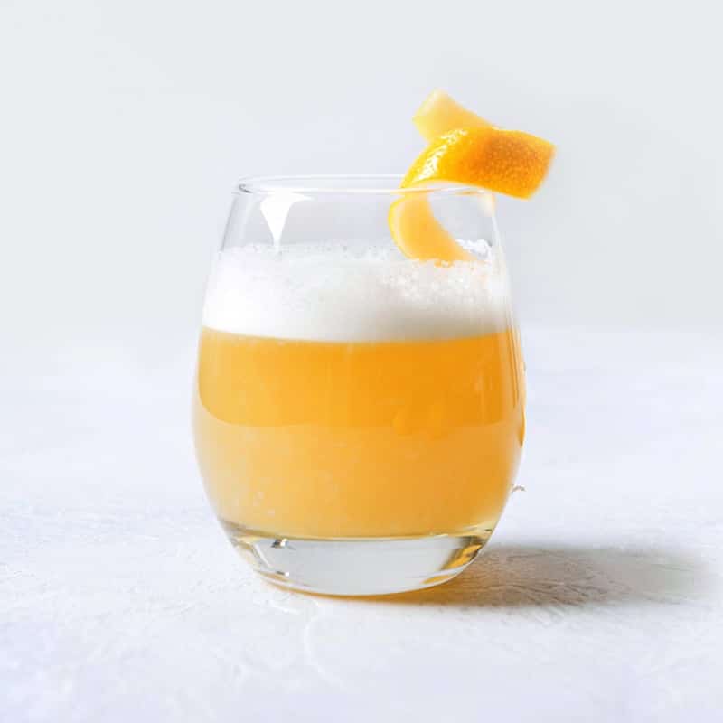 Glas mit Whisky Sour und einer Zitronenzeste